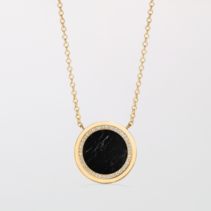 Gold necklace with a black stone pendant on a light gray background