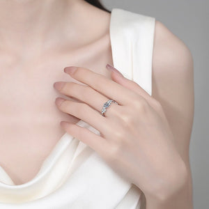 Hand wearing a silver ring with a diamond on a neutral background