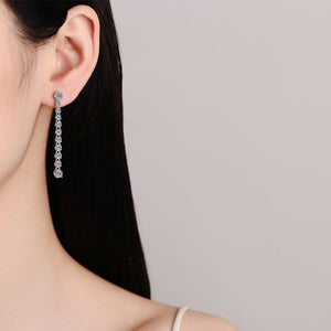 Close-up of a woman wearing diamond earrings with a plain background