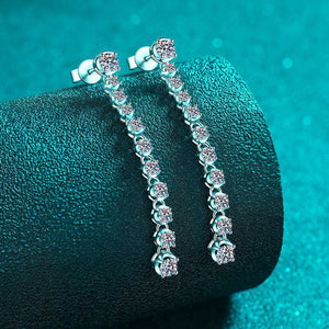 Silver earrings with gemstones on a textured teal surface