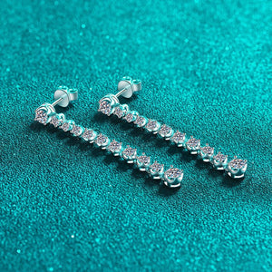 Pair of silver earrings with clear stones on a teal background
