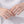 Two hands wearing silver rings on a plain background