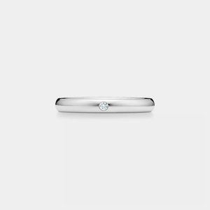 Silver ring with a small moissanite on a light gray background