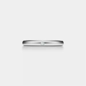 Silver ring with a small moissanite on a light gray background