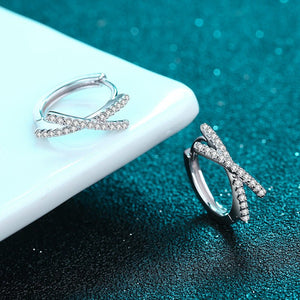 Silver hoop earrings on a teal surface with a blurred background