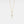 Gold necklace with a cross pendant on a light gray background