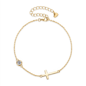 Gold bracelet with a small cross and round moissanite charm on a white background