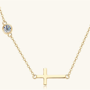 Gold necklace with a cross pendant and round gemstone on a white background