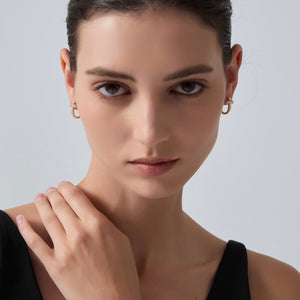 Close-up of a woman wearing gold earrings against a plain background