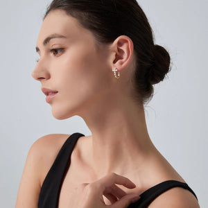 Woman wearing gold earrings on a plain background