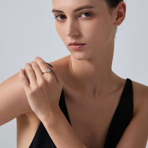 Woman wearing a black dress and diamond ring on a plain background