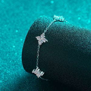 Silver bracelet with star-shaped charms on a textured black surface with teal background