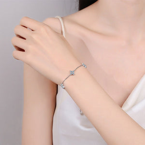 Silver bracelet with small stones on a person's wrist against a neutral background