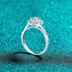 Silver ring with a large central gemstone on a teal glittery background