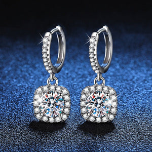 Pair of silver hoop earrings with round gemstones on a dark blue textured background