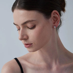 Close-up of a woman wearing a diamond earring against a plain background