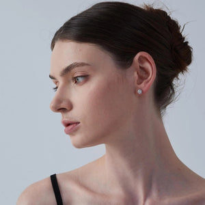 Woman wearing a diamond earring against a plain background