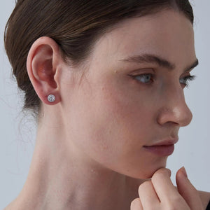 Close-up of a person wearing a diamond earring against a neutral background