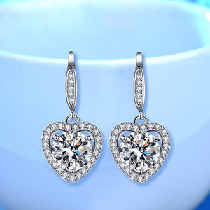 Heart-shaped earrings with clear gemstones on a light blue background
