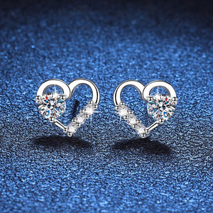 Heart-shaped earrings with clear gemstones on a blue textured background
