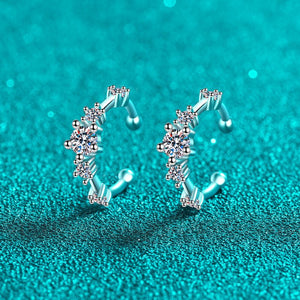 Silver hoop earrings with floral designs on a turquoise glitter background