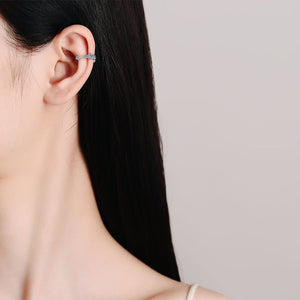 Close-up of a person wearing a silver earring with a neutral background