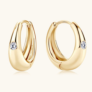 Gold hoop earrings with embedded diamonds on a white background