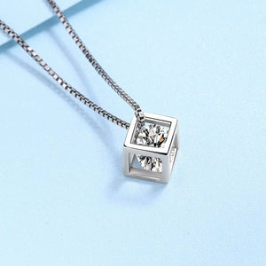 Silver necklace with a cube pendant on a light blue background