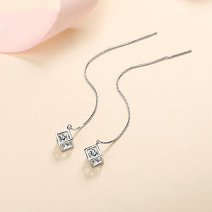 Silver necklace with square pendant on a beige background