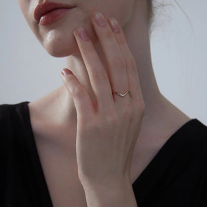 Close-up of a hand wearing a ring with a plain background