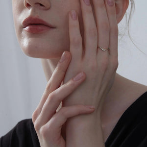 Close-up of a person's hand touching their face with a neutral background
