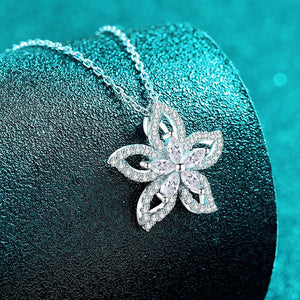 Silver flower-shaped pendant on a chain against a teal background