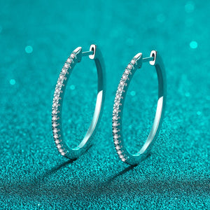 Silver hoop earrings with small diamonds on a teal background