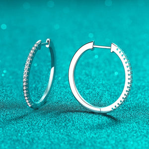Silver hoop earrings on a teal background