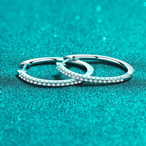 Two silver hoop earrings on a teal glittery background