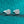 Pair of silver earrings with gemstones on a teal glittery background