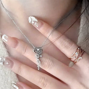 Silver necklace with a heart pendant on a hand with decorative nails.