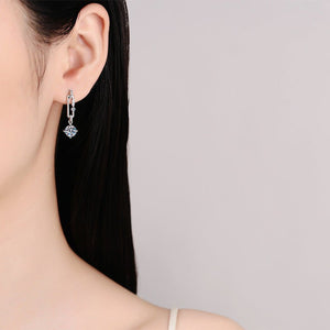 Silver earring with a clear gemstone worn by a person against a neutral background