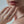 Close-up of a hand wearing a gold ring with diamonds, touching the chin against a neutral background.