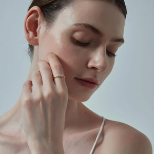 Woman wearing a gold earring against a neutral background