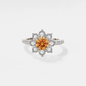 A moissanite gemstone set in a flower-shaped ring with a hypoallergenic platinum finish.