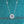 Silver necklace with a diamond pendant on a teal glittery background