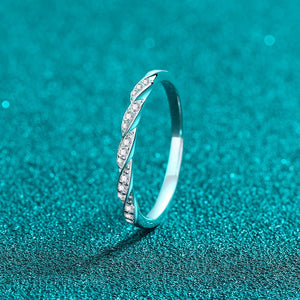 Silver ring with small moissanite on a teal textured background