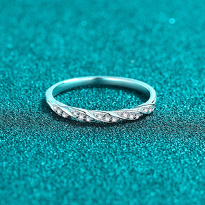 Silver ring with small moissanite on a teal textured background