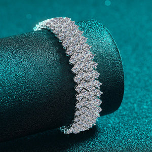 Silver bracelet on a teal cylindrical object with a teal background