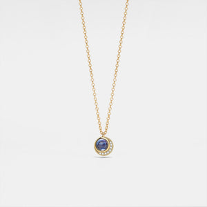 Gold necklace with a blue gemstone pendant on a light gray background