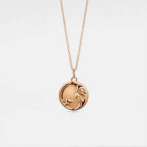 Rose gold necklace with a round locket featuring a moon face and star on a light gray background