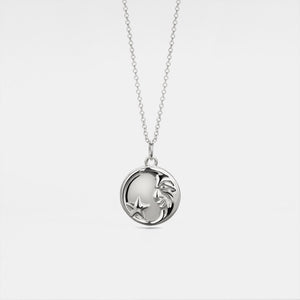 Silver necklace with a round locket featuring a moon face and star on a light gray background
