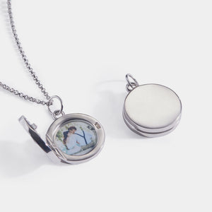 Sterling silver round locket necklace shown open and closed, featuring a smooth polished exterior and a photo insert inside, displayed on a delicate chain against a white background.