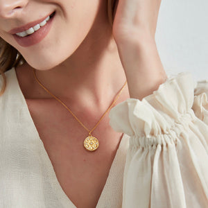 A woman wearing a gold photo locket necklace featuring a moon phase design with a star in the center.